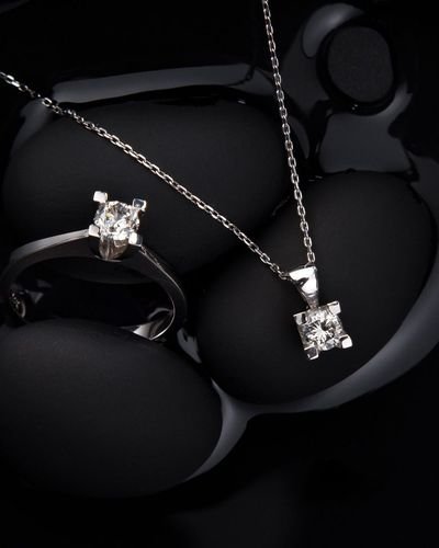 Gold ring and necklace pendant on black stone