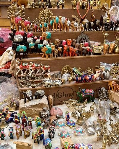 Brass and painted figurines of elephants, camels and deities on a stall shelf
