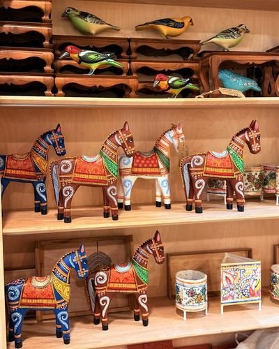 Hand-painted wooden horses and carved birds arranged on shelves