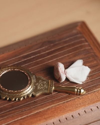An Aranmula kannadi, the handmade Kerala metal mirror, resting on a wooden table
