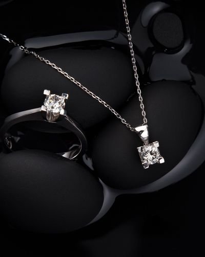 Silver ring and pendant necklace on black stone