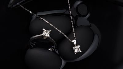 A diamond ring and matching pendant displayed on black forms