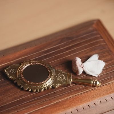 An Aranmula kannadi, the handmade Kerala metal mirror, resting on a wooden table